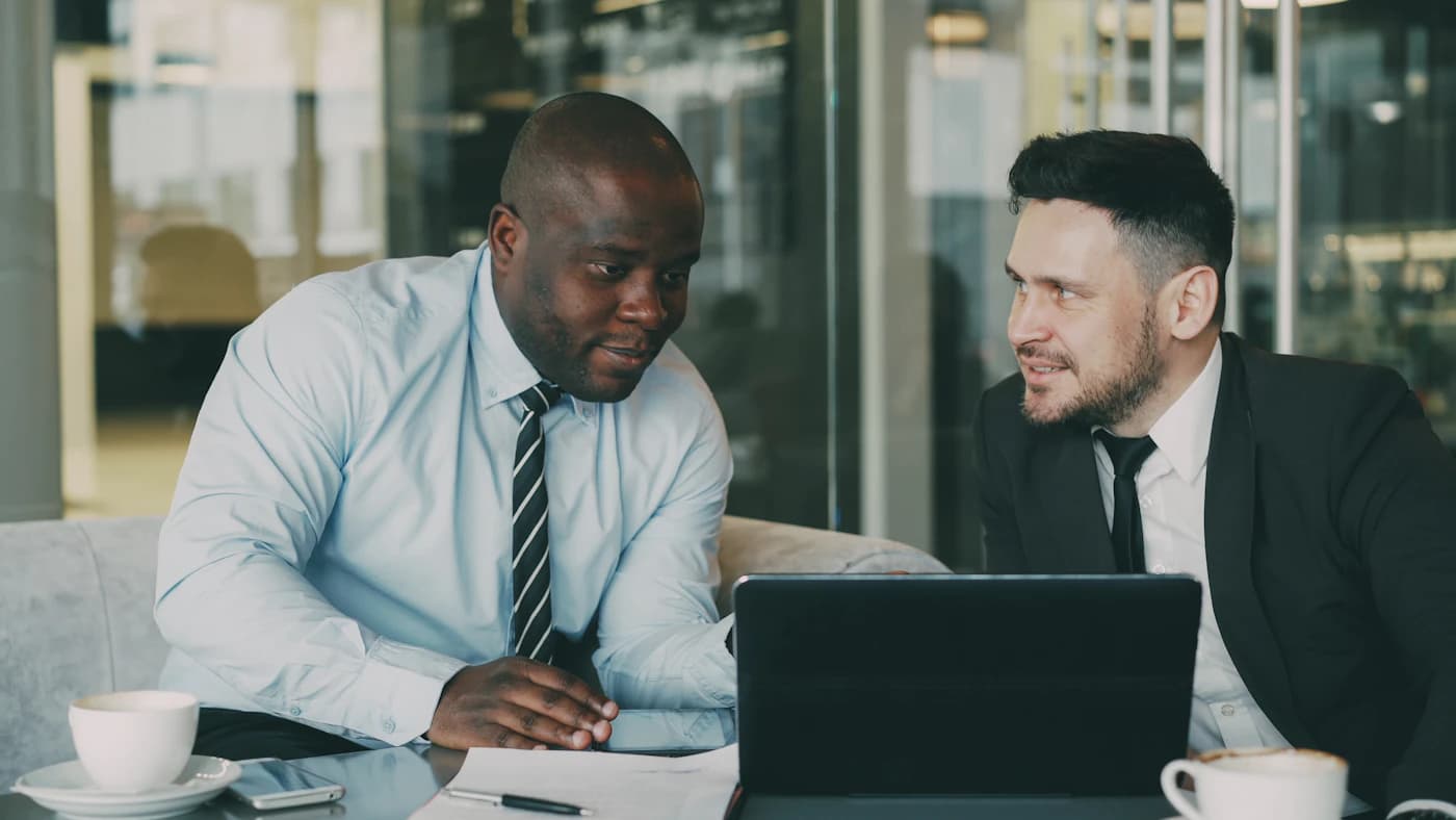 Twee professionals bespreken documenten aan een vergadertafel.